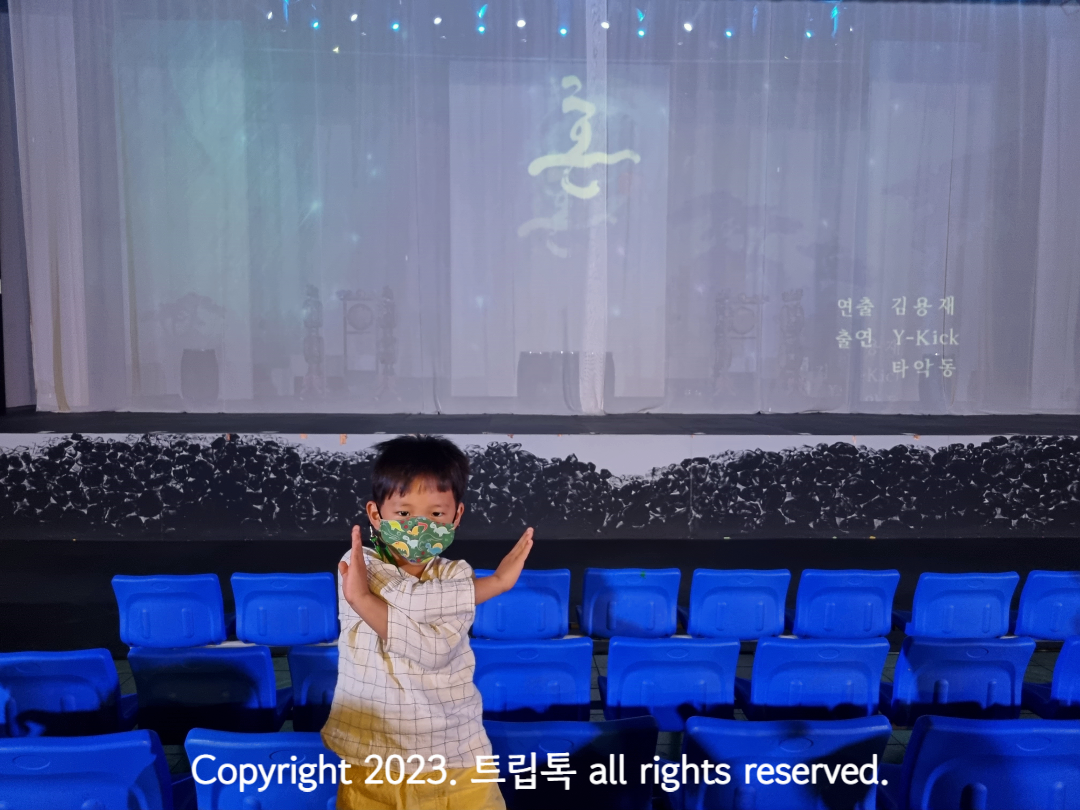 무대 정면에 하얀 커튼이 쳐있고 한 아이가 서있다.