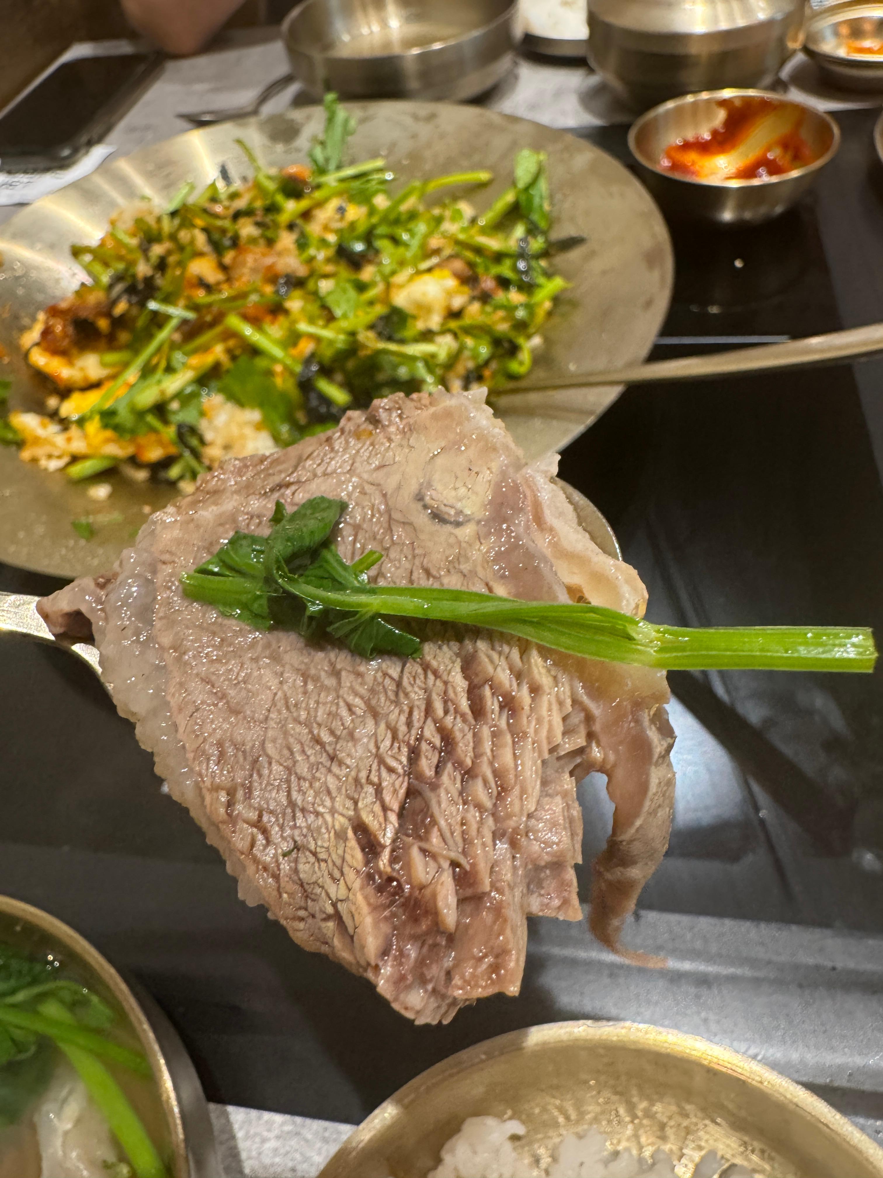 젓가락으로 집은 소고기와 미나리&amp;#44; 아래엔 밥그릇&amp;#44; 뒤로 비벼진 미나리 비빔밥과 밑반찬