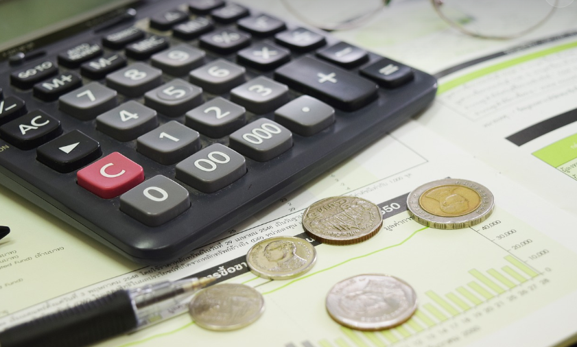 수수료를 계산하는 계산기와 옆에 동전들이 깔려있음