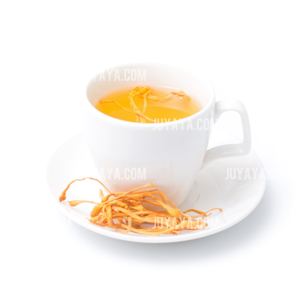 흰색 찻잔에 담긴 은은한 색의 건강 차와 곁들여진 말린 한약재. 전통적인 치유 음료를 상징.