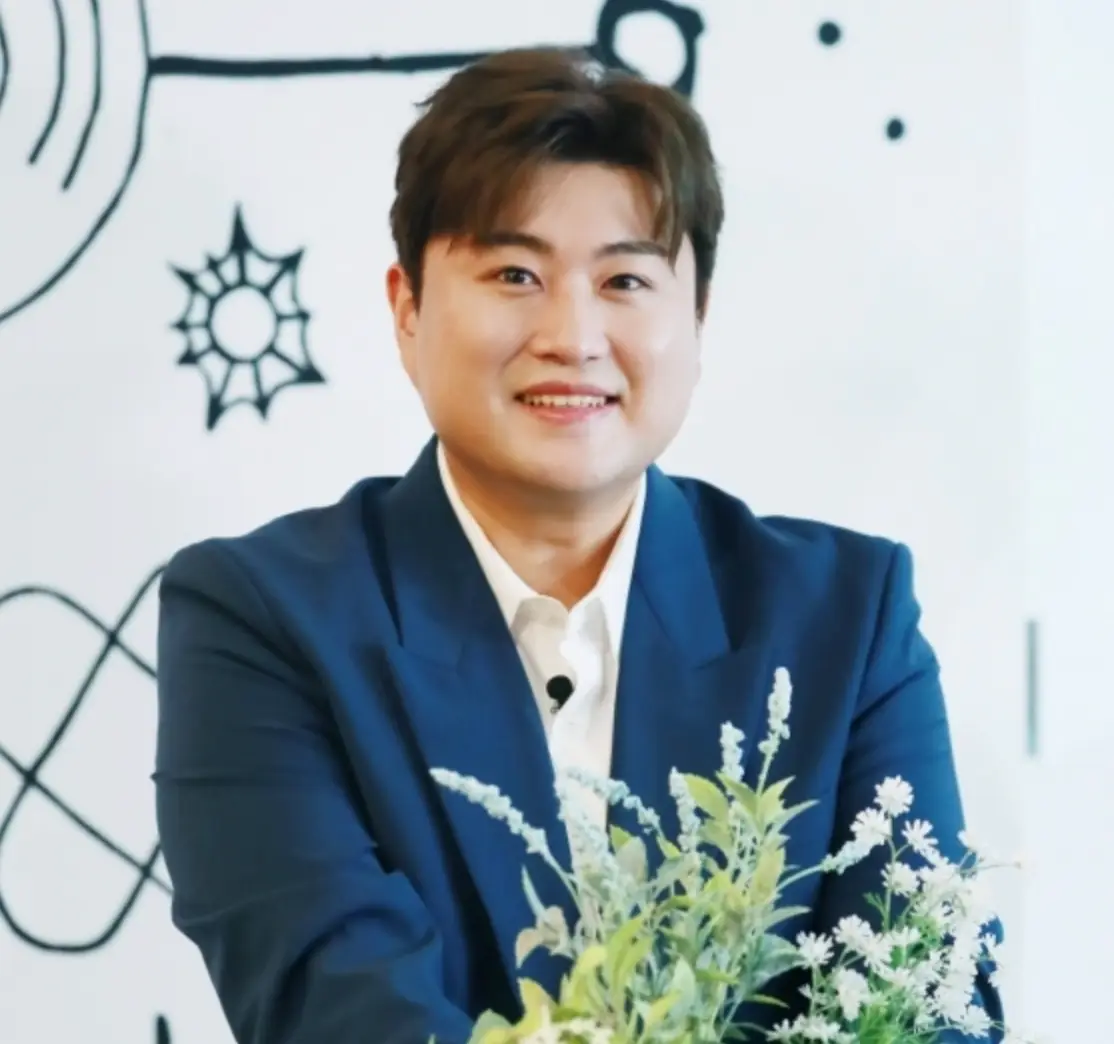 흰배경 파란쟈켓 흰 셔츠를 입고 꽃앞에서 미소짓는 김호중