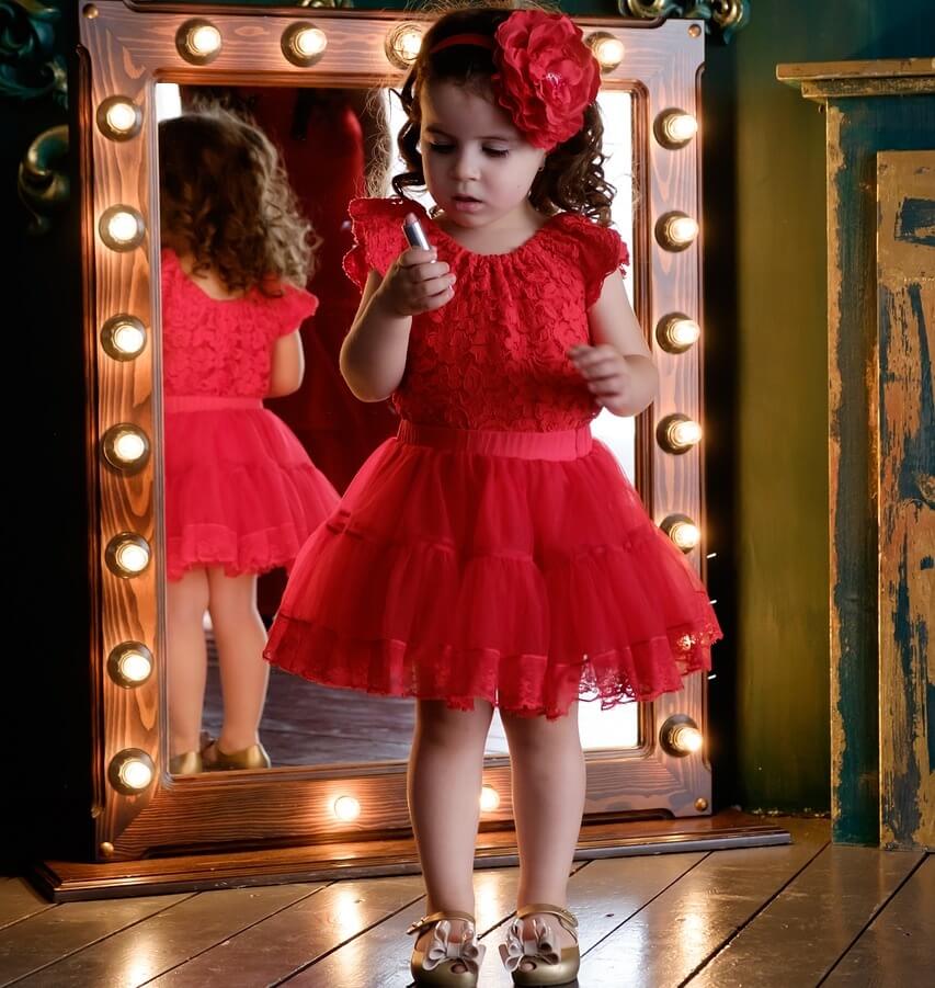 화려한 옷을 입고 거울을 보고 있는 아이 사진