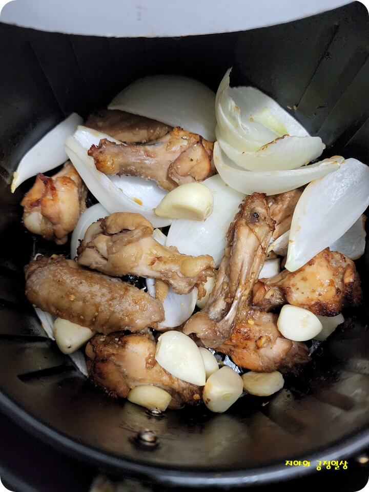 에어프라이기에 들어있는 닭고기, 양파와 마늘