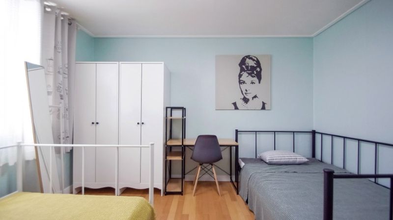 민트색 벽지로 도배된 깔끔한 2인용 침실. 화이트 옷장과 책상, 오드리 헵번 액자가 걸린 모던하고 차분한 분위기의 방 내부