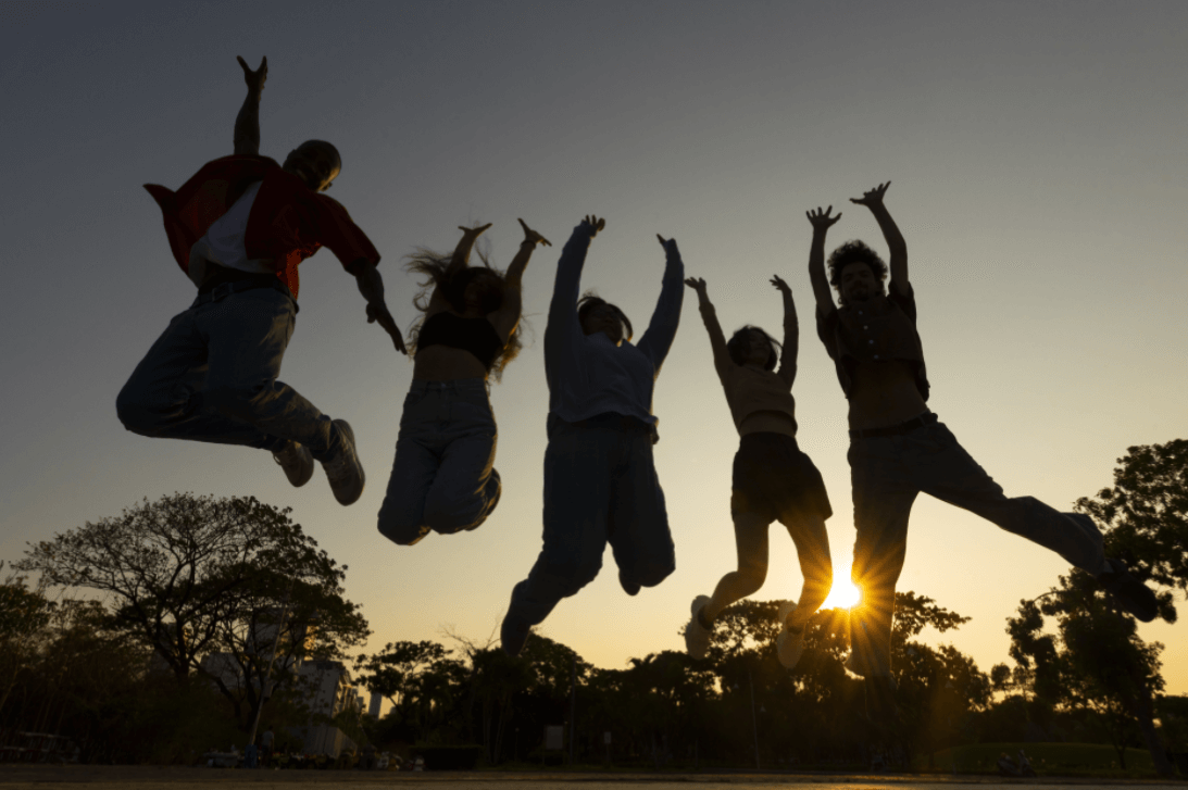 노을진 배경 속에서 점프하며 기뻐하는 청소년들 실루엣 → “자유롭고 활기찬 청소년기의 에너지와 공동체 정신을 표현한 장면”