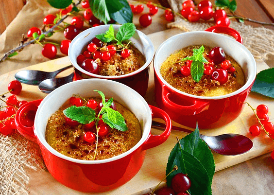 3개의 빨간 그릇에 크림 열매 디저트가 있다. 빨간 열매들이 토핑으로 올려졌다.