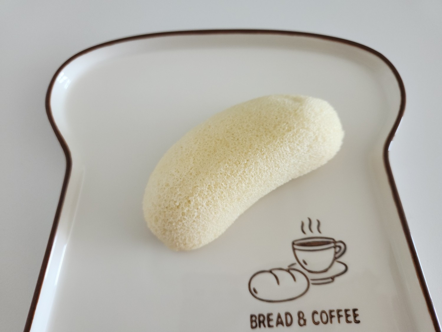 식빵 모양 접시 위에 바나나 모양 빵이 있다