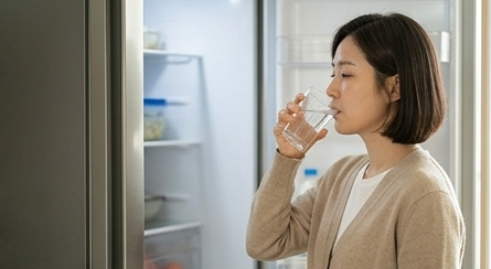 냉장고 앞에서 잠깐 물 한 잔을 마시며 숨을 고르는 30대 엄마