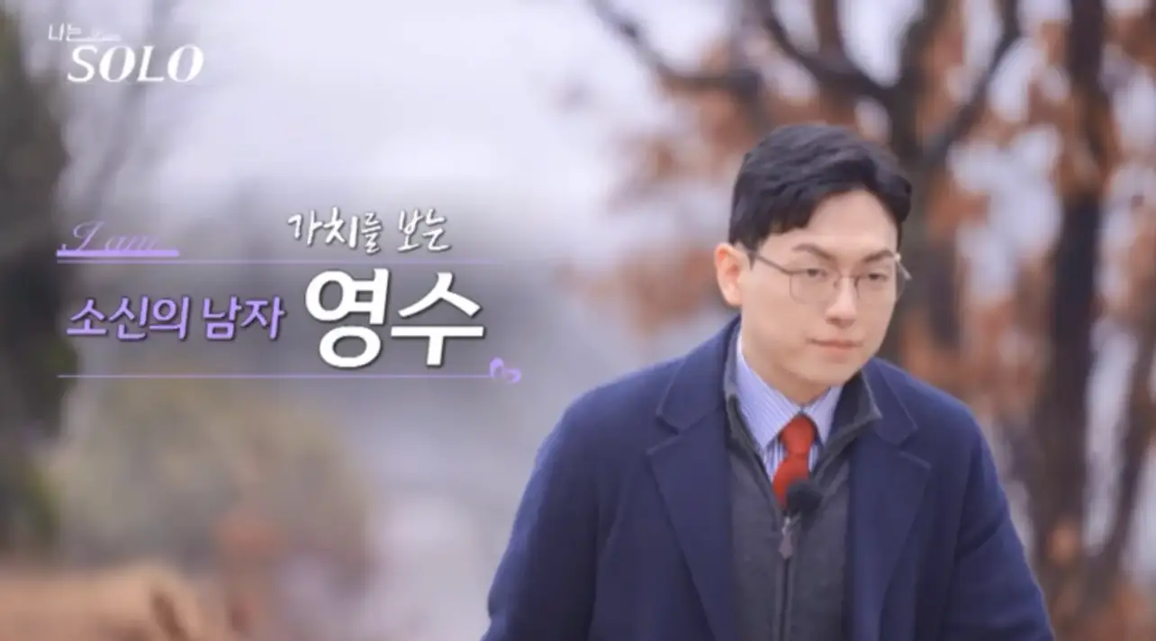 가을 나무 숲 좌측 보라글씨 소신의 남자 영수 우측 옆 파란 쟈켓을 입고 안경을 쓴 채 입을 꽉 다물고 있는 영수