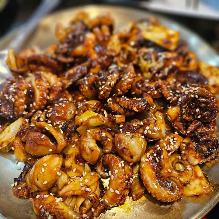 빨갛고-잘익은-쭈꾸미가-위에-깨가-뿌려져있다-sesame- seeds-on-the-top-of-small-octopus-with-red-spicy-sauce
