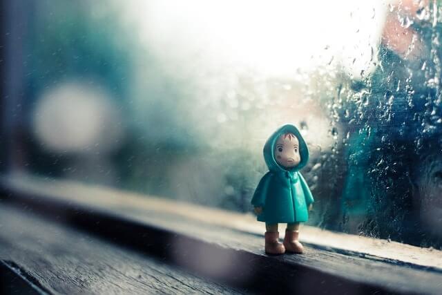 비내리는 창가에 우비를 입은 작은 인형이 있는 모습