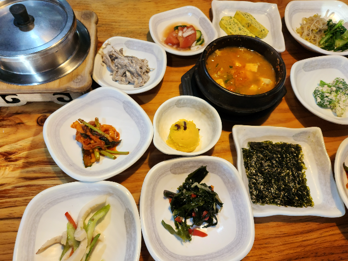 계란, 버섯, 샐러드, 감자 등이 담긴 접시가 테이블 위에 있다