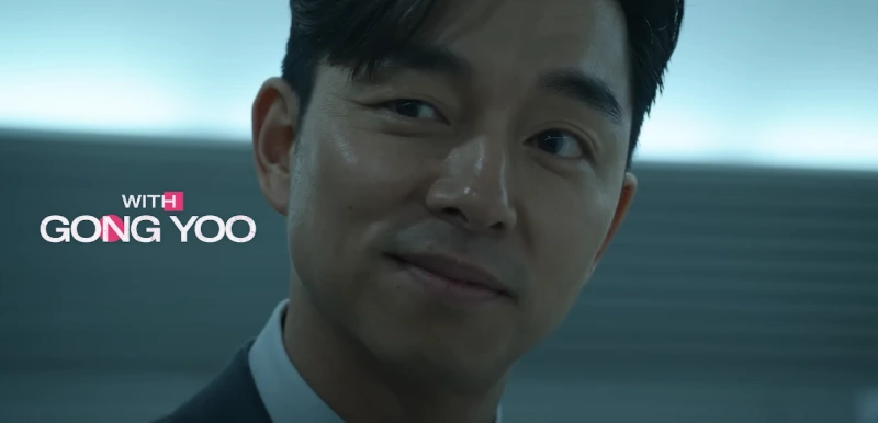 어느 지하철 승강장을 배경으로 양복을 입고 한쪽 입꼬리를 살짝 머금고 누군가를 바라보는 오징어 게임의 양복남을 연기하는 공유