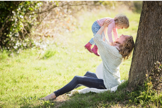 들판에서 아이를 안고 웃는 엄마, 양육 가정의 따뜻한 일상 모습