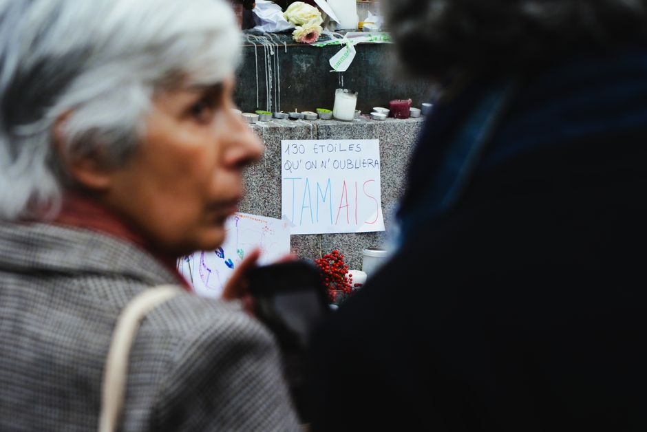 Emotional scene at a memorial vigil with text sign and candles.