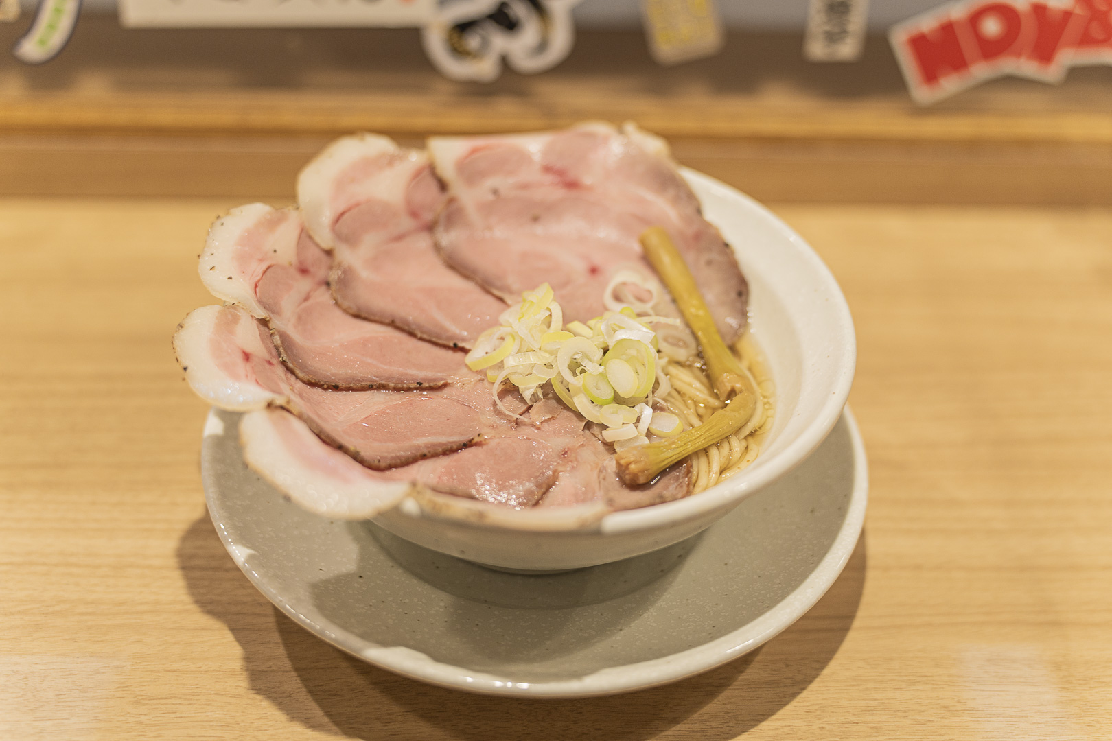 Menya Yuko: a white bowl of ramen covered with chashu slices, scallion and bamboo shoot.