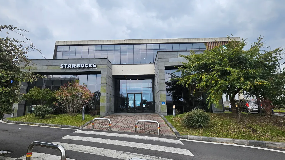 스타벅스-제주도남DT점-외부-정면-회색건물과-오른쪽-나무