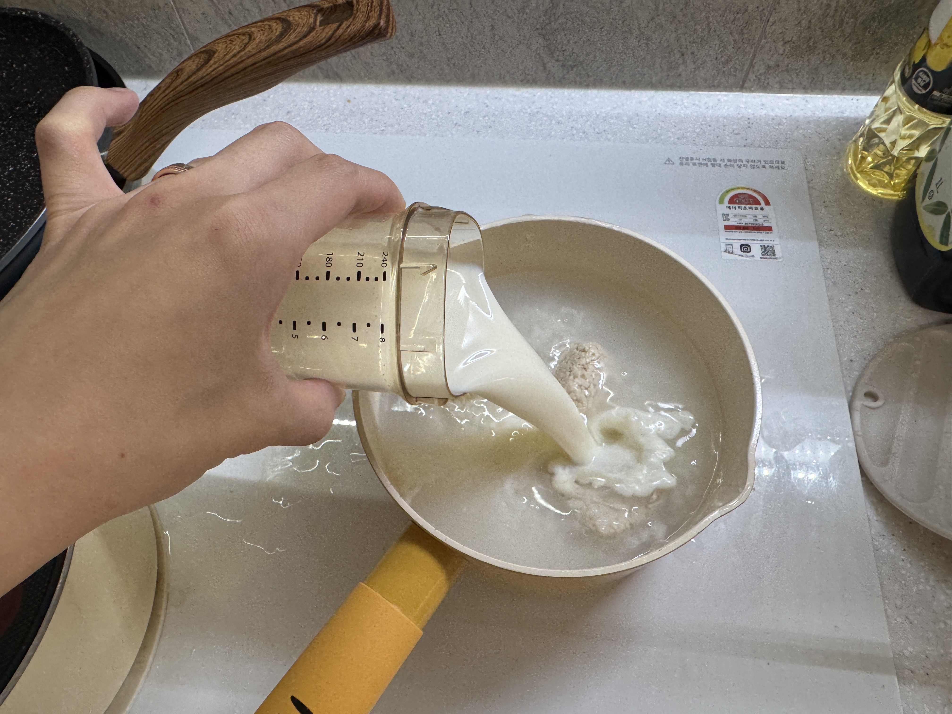 냄비에 불린 쌀, 닭고기, 단호박을 끓이다가 분유를 넣는 사진