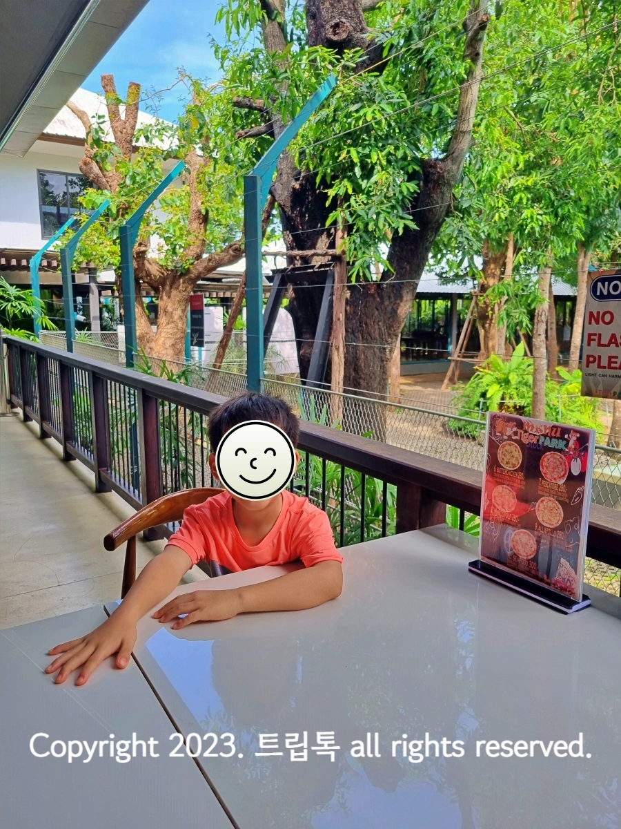 아이가 야외 테이블에 앉아서 순서를 기다린다.