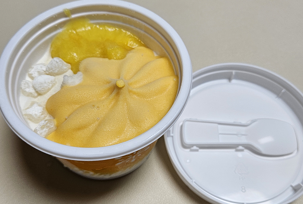 망고 빙수 뚜껑을 연 모습. 뚜껑 안쪽에 작은 숟가락이 있고 내용물은 우유 얼음 위에 망고 아이스크림, 망고 잼, 작은 찹쌀떡 6~7개정도 올려져 있다