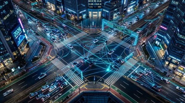 A top-down view of a complex city intersection in 2026, autonomous vehicles moving in perfect harmony, digital data overlays showing V2X communication paths between cars and traffic lights, neon blue light accents, hyper-realistic.
