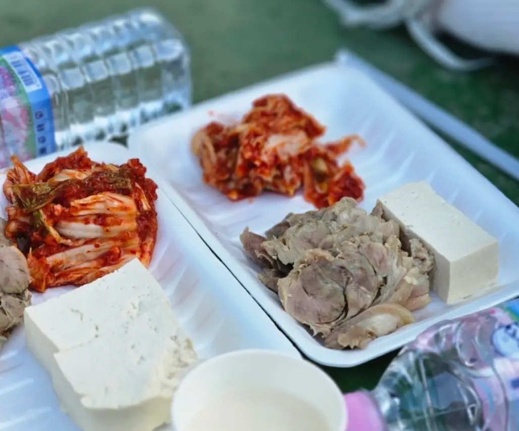 수육런-흰색 일회용 접시안에 놓인 수육과 흰색 두부 김치이미지 양옆 생수 2병