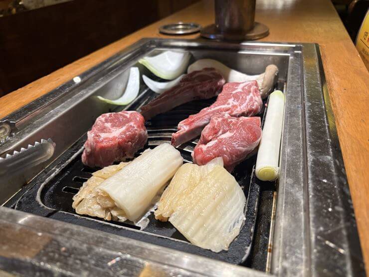 그릴에 구워지고 있는 양고기이다.
양고기 주변에 백김치와 파, 양파, 버섯도 함께 있다.