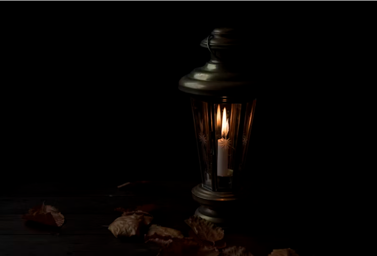 어두운 배경 위에 놓인 빈티지 촛대 안에서 작은 촛불이 은은하게 타오르고 있는 이미지