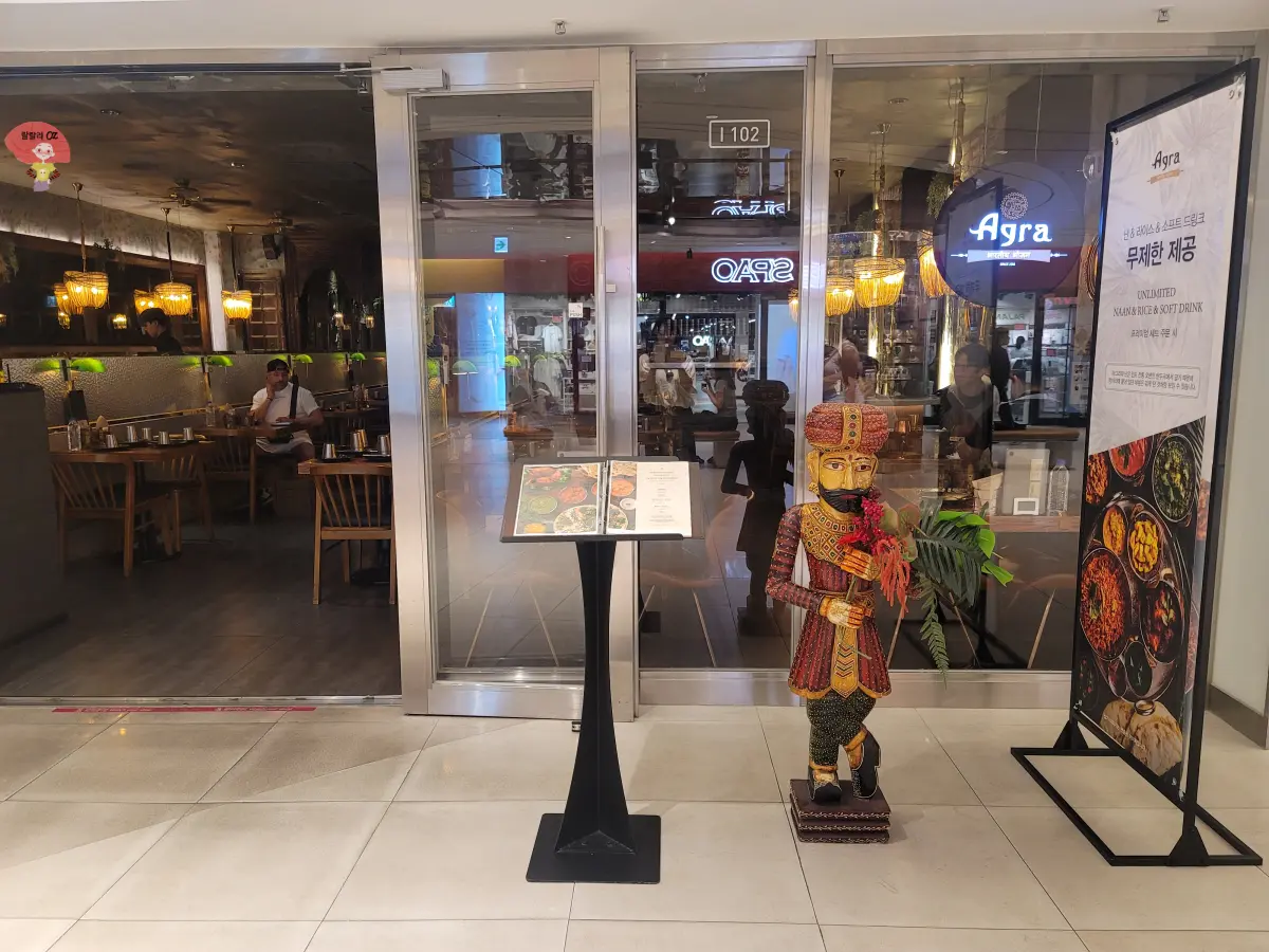 서울-강남-스타필드-코엑스점-인도음식점-아그라-외관-입구-오른쪽-스탠딩-메뉴와-인도-전통-인형이-보임