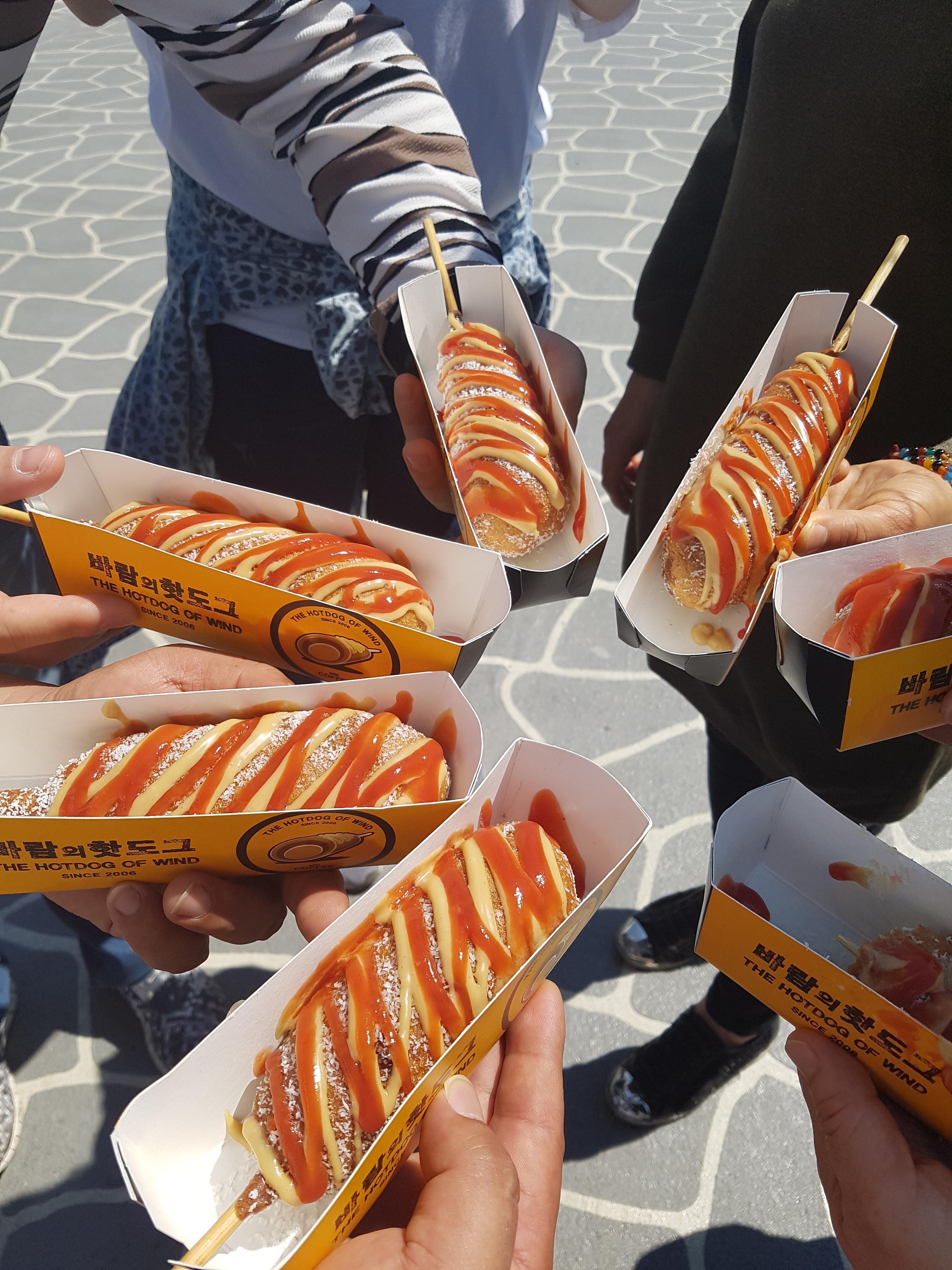 머스터드와 케첩이 듬뿍 뿌려진 먹음직스러운 바람의 핫도그 사진