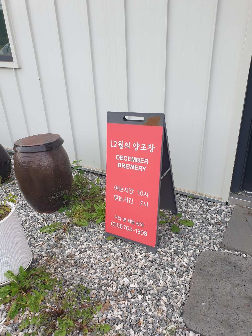 건물 앞에 붉은색 입간판이 있다. 옆에는 장독대도 보인다.