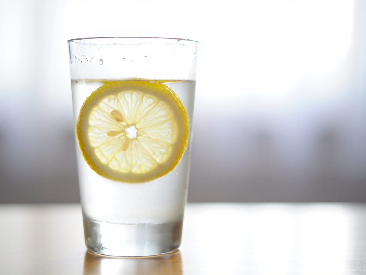 잔에 물과 레몬 한 조각이 담겨있는 모습
