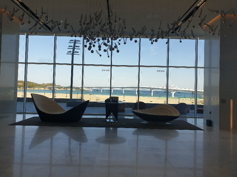 로비 한 쪽면은 유리로 되어 있어 바다가 보인다. 그 앞 소파가 바다쪽으로 놓여 있다.