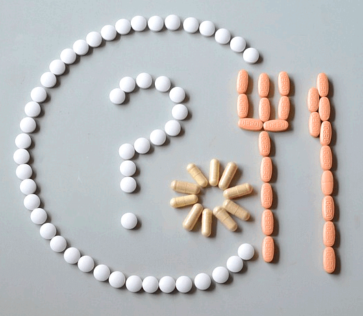 하얀 알약들로 둥그런 접시모양의 원을 만들고 그 안에는 물음표가 있다. 오른쪽엔 분홍색 알약으로 포크와 나이프를 만들었다.