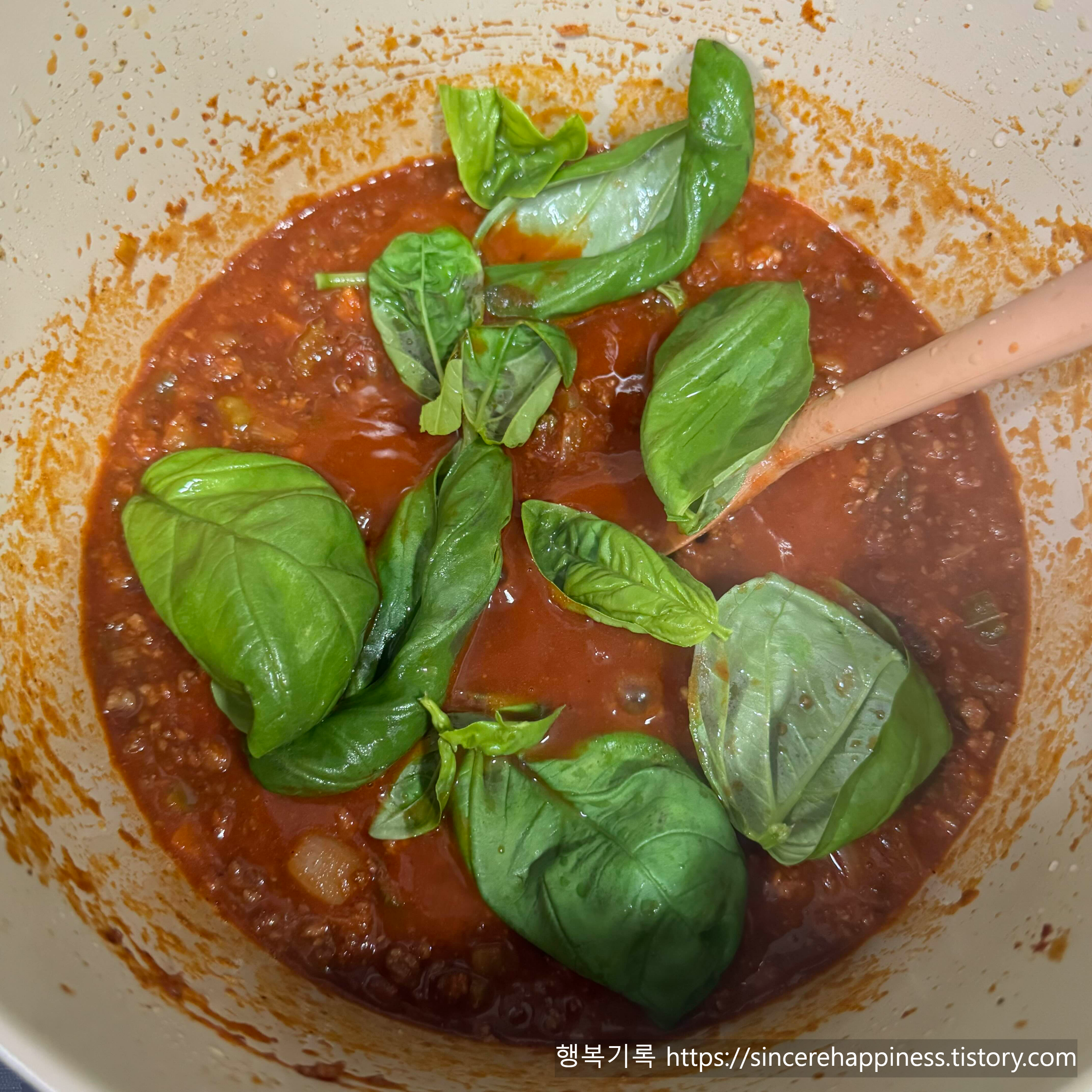 끓고 있는 토마토 라구소스에 국내산 생바질을 넣어 풍미를 살리는 모습