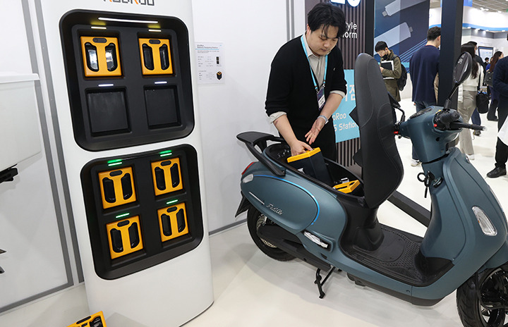 서울 강남구 코엑스에서 열린 배터리 산업 전시회에서 관계자가 전기이륜차용 배터리팩과 배터리 교환형 충전장치를 시연하고 있다.