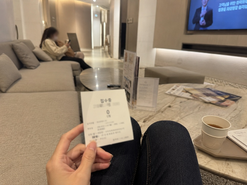 리쥬란 부작용 상담을 위해 피부과 대기실 소파에 앉아 접수증을 들고 기다리는 모습