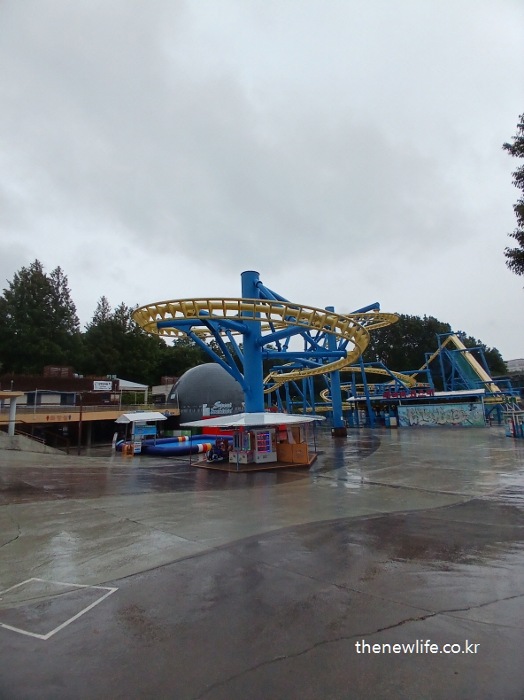 Yellow and blue rollercoaster structure in the center of an empty amusement area in Children’s Grand Park./서울 어린이대공원 내 텅 빈 놀이공원에 위치한 노란색과 파란색 롤러코스터 구조물.