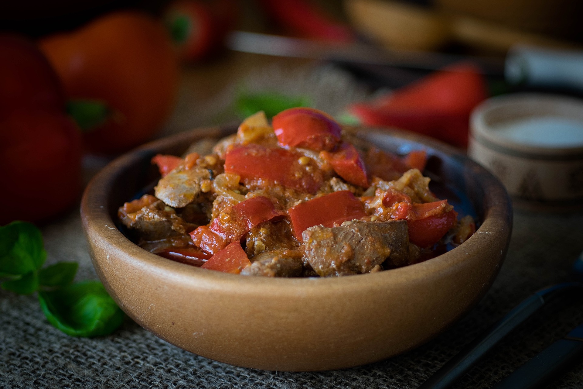 검은 바닥 위에 고동색의 동그란 접시를 두고 그 속에 간과 야채와 양념을 넣고 볶은 요리를 가득 담아두고 찍은 사진