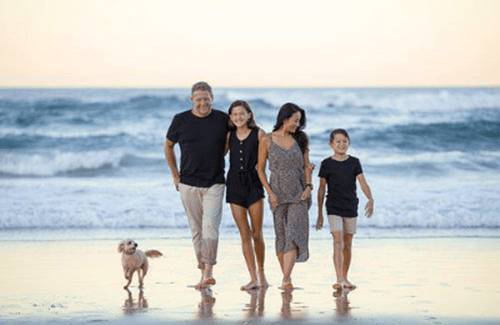 바닷가에서 가족이 행복하게 걸어가는 사진입니다.