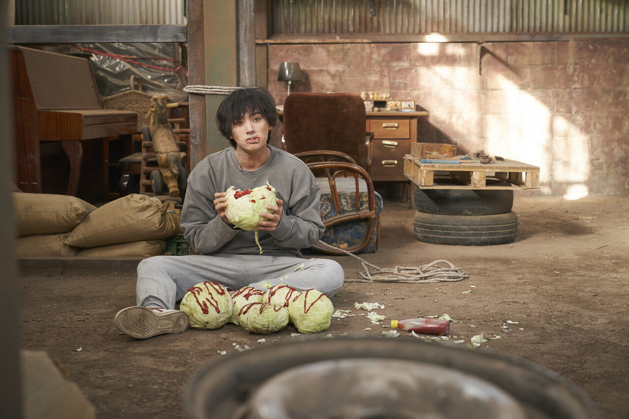 기묘한 가족 속 좀비인 쫑비가 케첩 묻은 양배추를 먹고 있는 모습