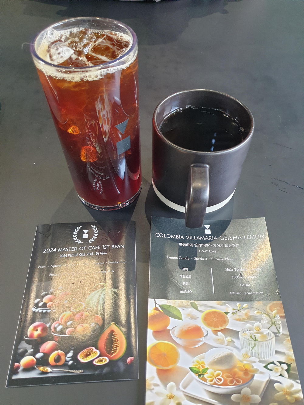 컵노트와 함께 아이스커피 한 잔과 핫 커피 한 잔이 테이블 위에 올려져 있다.