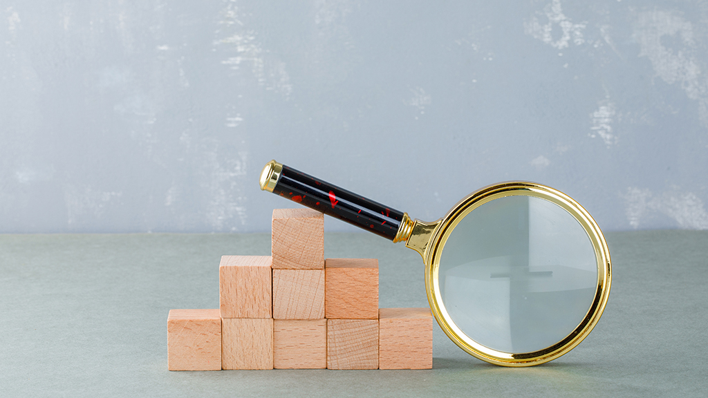 산 모양으로 쌓긴 정육면체 나무 블럭과 비스듬히 기대져 있는 돋보기