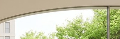 따뜻한 베이지 톤의 미니멀한 실내 공간과 통유리창 너머 푸른 정원이 조화를 이루는 브랜드 플래그십 스토어의 전경입니다. 원목 테이블 위의 커피 한 잔과 세련된 계단 구조가 여유롭고 지적인 라이프스타일의 분위기를 자아냅니다.