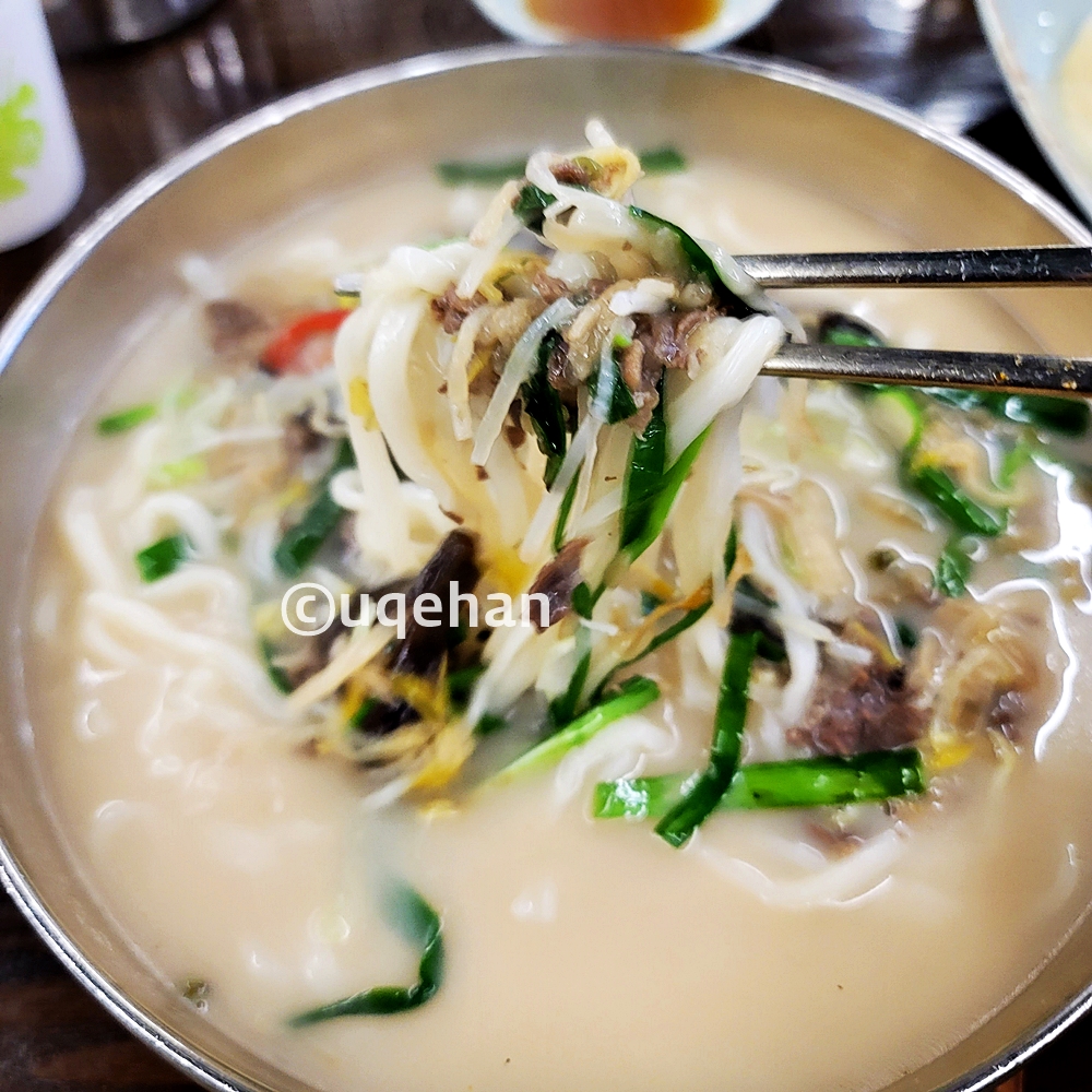 양주 밀곳 칼국수 사진이다. 쑥주와 부추 그리고 칼국수면을 젓가락으로 들고있다.