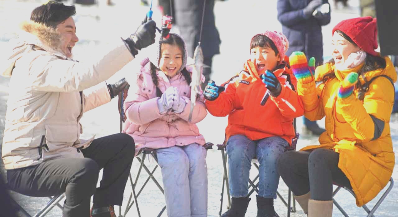 얼음판 위 낚시 구멍을 사이에 두고 산천어 낚시를 하는 가족 단위 여행객이다. [ⓒ한국관광공사]