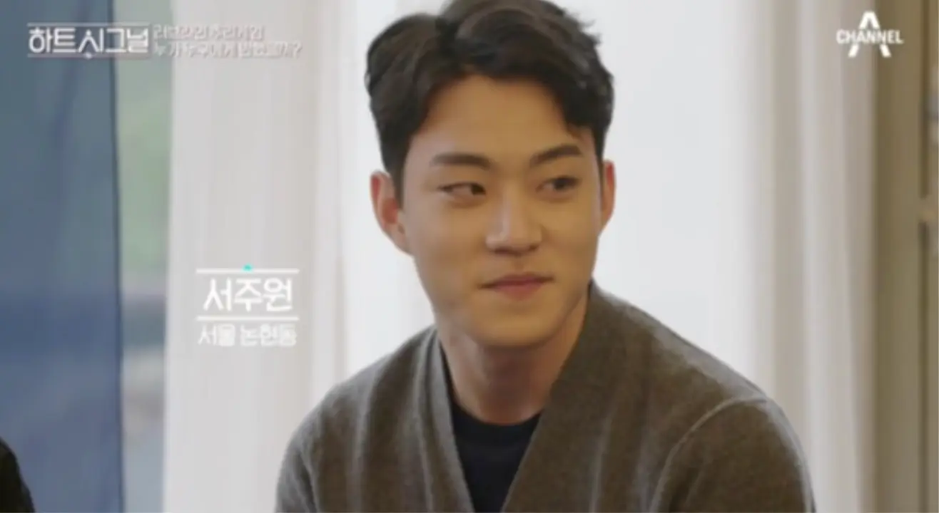 베이지색 커튼 앞 진한 회색 가디건을 입고 옆을 보며 미소짓는 남자 출연자 좌측 옆 흰글씨 서주원 서울 논현동