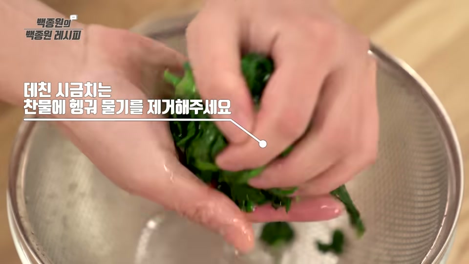 데친 시금치를 찬물에 헹궈 물기를 짜는 장면