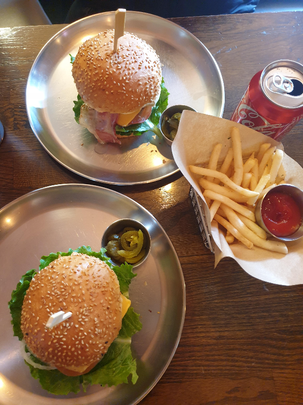 햄버거 2개와 프렌치프라이 그리고 콜라가 테이블 위에 있다.