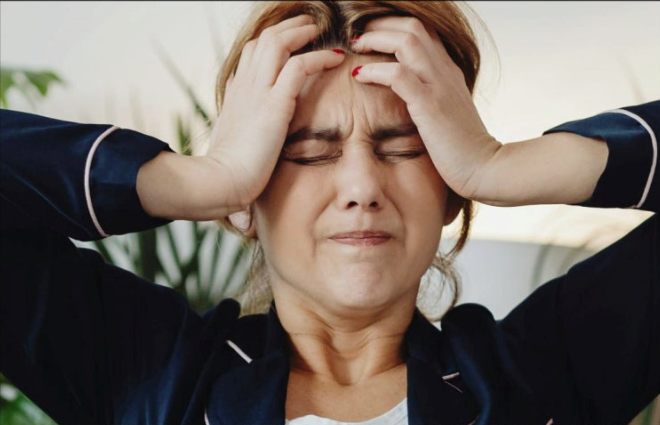 머리가 아픈 여성이 머리를 꾹 누르고 있는 모습